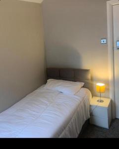 a bedroom with a white bed with a lamp on a night stand at Beautiful stylish house near town centre in Rugby