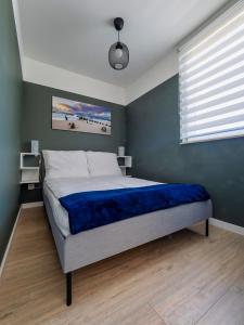 a bedroom with a bed with blue sheets and a window at Apartament Baltic Sunrise in Sztutowo