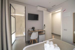 a bedroom with a bed and a desk and a television at Hotel La Milagrosa in Alicante