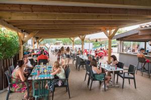 eine Gruppe von Menschen, die an Tischen in einem Restaurant sitzen in der Unterkunft Camping maeva Club Les Rivières in Canet