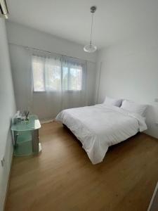 a white bedroom with a large bed and a table at Amazing 2-bedroom apartment with pool!! in Limassol