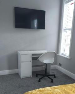 a white desk with a chair and a television on a wall at Beautiful stylish house near town centre in Rugby