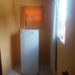 a small white refrigerator in a room with a window at Pousada Só Alegria in Fortaleza