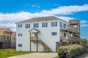 a large white house with a wooden staircase at Boss's Playhouse in Kill Devil Hills