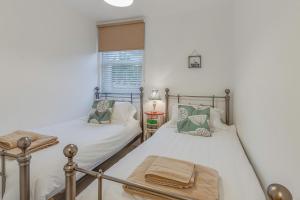 two twin beds in a room with a window at Jurassic View Apartment in Lyme Regis