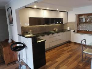 a kitchen with white cabinets and a black counter top at Apartamenty pod Dzikowcem in Boguszów-Gorce
