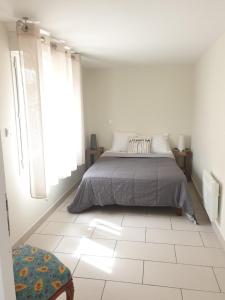 a bedroom with a bed and a white tiled floor at Appartement le loft in Saintes-Maries-de-la-Mer