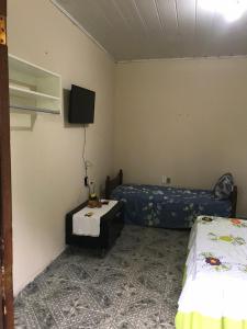 a room with two beds and a tv on the wall at Flat da Praia Rio das Ostras in Rio das Ostras