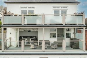 a house with a large deck with glass doors at Jurassic View Apartment in Lyme Regis