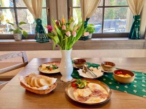 una mesa con platos de comida y un jarrón de flores en Stará Zvonica, en Nižná Boca