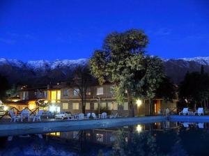 una casa con piscina por la noche con montañas cubiertas de nieve en Hotel El Hornero Spa en Merlo