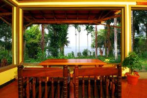 a table and two chairs on a porch with a window at SaffronStays Coorg Toddy Farms, Coorg in Madikeri