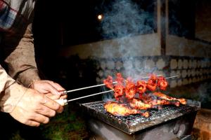 a person cooking meat on a grill with tongs at SaffronStays Coorg Toddy Farms, Coorg in Madikeri