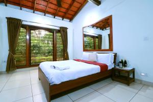 a bedroom with a large bed in a room with windows at SaffronStays Coorg Toddy Farms, Coorg in Madikeri