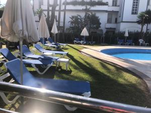 a group of lounge chairs and umbrellas next to a swimming pool at Dominion Beach House in Estepona