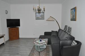 uma sala de estar com um sofá preto e uma televisão em Ferienwohnungen Öker - Whg 4 em Grömitz