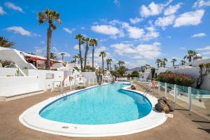 Una piscina en un resort con palmeras y edificios. en Puerto Chico X, en Playa Blanca