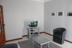 uma sala de estar com uma cadeira e uma televisão em Apartamento Urb. Vila Nova, Lote 5 em Armação de Pêra