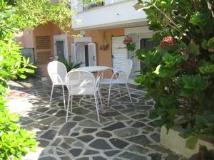 a patio with white chairs and a table in front of a house at Muses Studios Sami in Sami