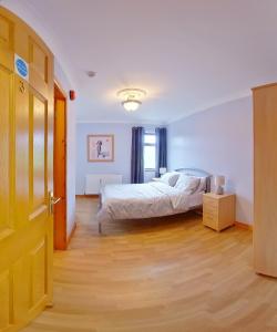 1 dormitorio con 1 cama y suelo de madera en The Coach Inn en Strabane