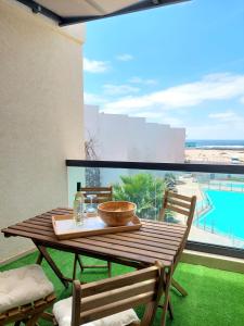 a wooden table on a balcony with a view of the beach at Deep Blue Cotillo II by Sea You There Fuerteventura in Cotillo