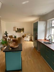 a kitchen with green cabinets and a living room at Feriehus i skøn natur in Stenstrup
