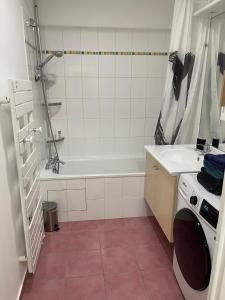 a bathroom with a tub and a sink and a washing machine at Superbe 3 PIECES face gare TGV / RER de Massy in Massy