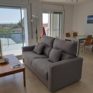 a living room with a gray couch and a table at DELTAEBRO PISCINA in L'Eucaliptus
