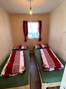 two beds in a small room with a window at Bungalow Li Presi in Camping Cavresc, Via dal Cavresc 1, 7746 Le Prese-Poschiavo in Poschiavo