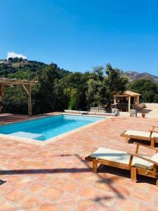 a swimming pool with two loungers and two chairs at Villa de standing, piscine chauffée,Balagne, Pietralba in Pietralba