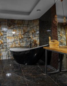 a black tub in a bathroom with a stone wall at Malinówka in Ujsoły