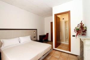 sypialnia z białym łóżkiem i lustrem w obiekcie Albergo Maccagno w mieście Maccagno Inferiore
