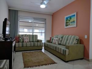 a living room with two couches and a television at Apartamento amplo próximo a praia - Faça tudo a pé in Guarujá