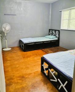 a room with two beds and a fan at OYO Home 90491 Flinstone Lodge in Kota Kinabalu
