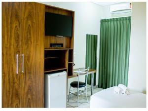 a room with a tv and a desk with a bed at Steel Valley Hotel in Ipatinga