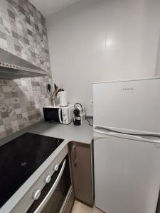 a kitchen with a white refrigerator and a microwave at CÉNTRICO ÁTICO EN TORREDEMBARRA CON PARKING. in Torredembarra