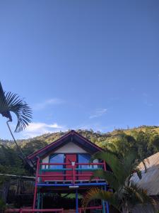 une maison avec une porte rouge et un palmier dans l'établissement Casa de Campo La Prosperidad, à Bobadilla