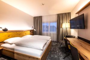 a hotel room with a bed and a desk at Sleep in Premium Hotel Eggenburg in Eggenburg