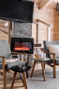 a living room with a fireplace with two chairs and a table at Eco Domki Podhalanka in Witów