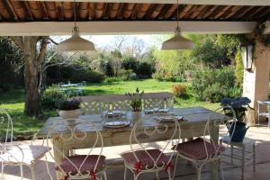 una mesa de madera y sillas en un patio en Les Romarins B&B, 10 min d'Uzès, piscine et grand jardin, Table d'hôte, en Uzès