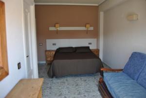 ein Schlafzimmer mit einem Bett und einem blauen Sofa in der Unterkunft Hotel Hoya in Noja