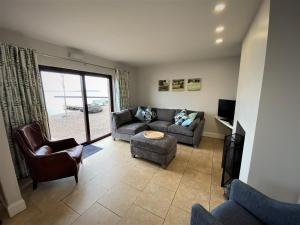 a living room with a couch and chairs and a tv at Tullybay Holiday Homes in Tully