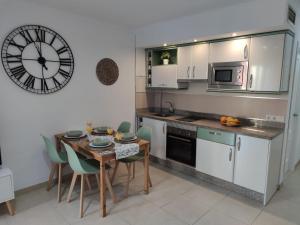kuchnia ze stołem i zegarem na ścianie w obiekcie Apartamento El Capacho w mieście Torrox Costa