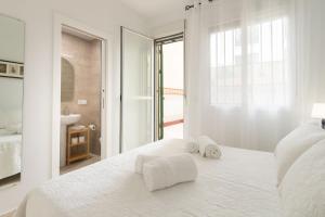 Un dormitorio blanco con una cama con toallas. en Bordador Central Courtyard by Valcambre, en Sevilla