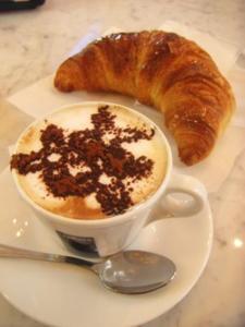 a cup of coffee and a croissant on a plate at B&B Alloggi Buonasera in Pozzallo