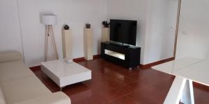 salon z telewizorem i białą kanapą w obiekcie PLAYA ALMARDA CORINTO, PISCINA, WIFI,2 TERRAZAS, BARBACOA,TRANQUILo w mieście Sagunto