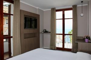 a bedroom with a bed and a tv and a balcony at Hotel Ristorante Vapore in Faggeto Lario 