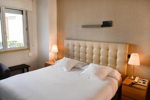 1 dormitorio con 1 cama blanca grande y 2 lámparas en Alda Don Carlos en Santander