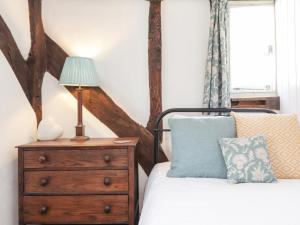 Tudor Cottage في ساندويتش: غرفة نوم مع سرير وخزانة مع مصباح