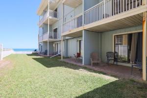 a large apartment building with a lawn in front of it at Coastal Waters in New Smyrna Beach